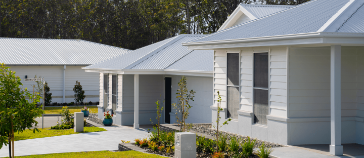Allam Homes Monterey Estate COLORBOND steel cool roofing. Modern suburban houses with light gray colorbond steel roofs, surrounded by landscaped gardens and trees,