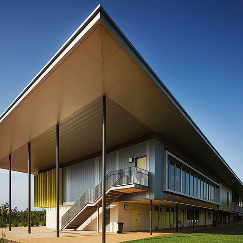 Cantilevered roofs sitting lantern-like atop the weightiness of a concrete block work-base, MacKillop Catholic College in the Northern Territory, roofing, wall cladding, soffits and flashing made from COLORBOND® steel in the colours Windspray®, Jasper®, and Shale Grey™