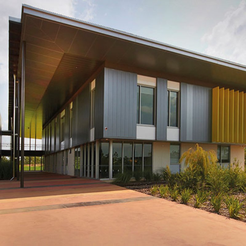 Cantilevered roofs sitting lantern-like atop the weightiness of a concrete block work-base, MacKillop Catholic College in the Northern Territory, roofing, wall cladding, soffits and flashing made from COLORBOND® steel in the colours Windspray®, Jasper®, and Shale Grey™