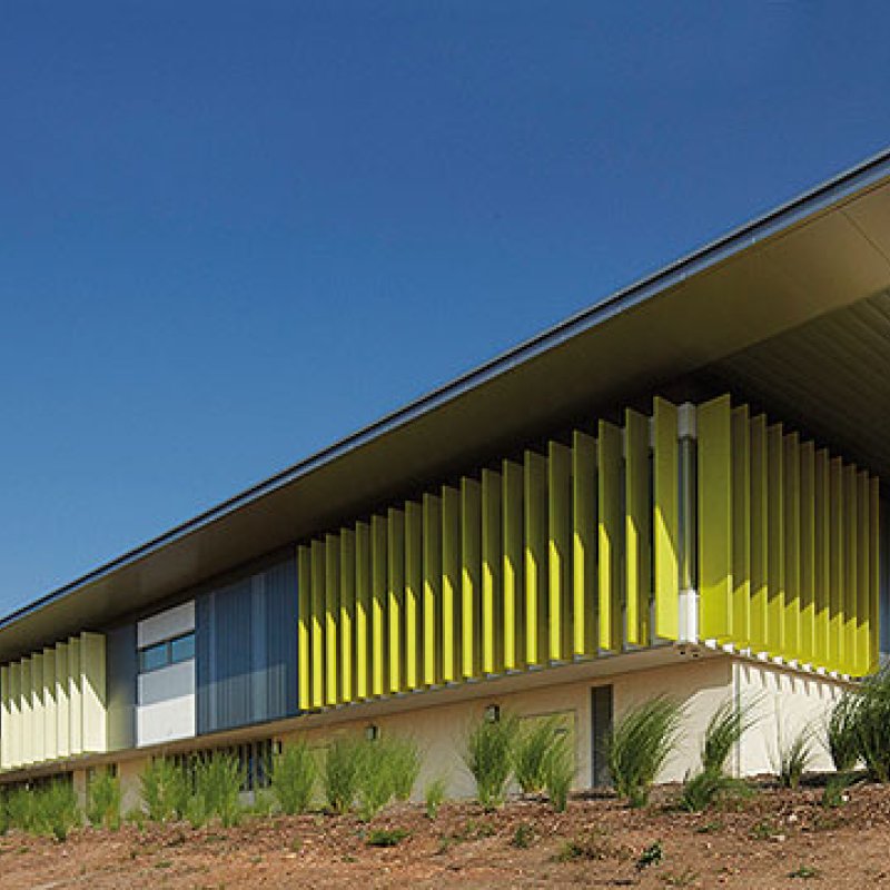 Cantilevered roofs sitting lantern-like atop the weightiness of a concrete block work-base, MacKillop Catholic College in the Northern Territory, roofing, wall cladding, soffits and flashing made from COLORBOND® steel in the colours Windspray®, Jasper®, and Shale Grey™