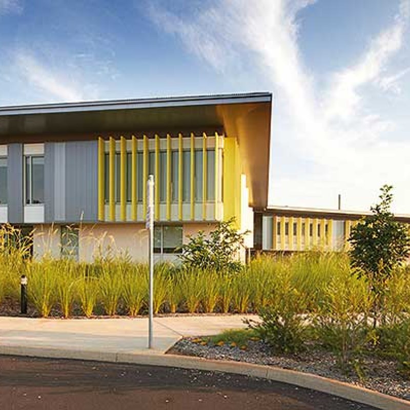 Cantilevered roofs sitting lantern-like atop the weightiness of a concrete block work-base, MacKillop Catholic College in the Northern Territory, roofing, wall cladding, soffits and flashing made from COLORBOND® steel in the colours Windspray®, Jasper®, and Shale Grey™