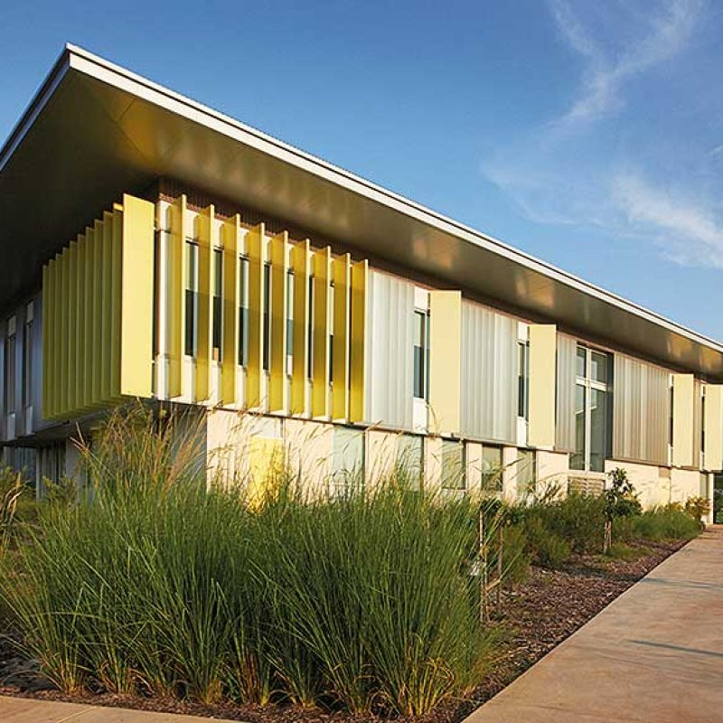 Cantilevered roofs sitting lantern-like atop the weightiness of a concrete block work-base, MacKillop Catholic College in the Northern Territory, roofing, wall cladding, soffits and flashing made from COLORBOND® steel in the colours Windspray®, Jasper®, and Shale Grey™